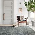 Harlow Denim Charcoal Rug styled in modern room with chair, side table, and large potted plant