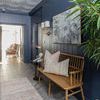 Runner-sized rug placed in hallway with dark blue paneled walls, mid-century bench, and decorative pillows