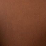 Close-up of wood armrest detail adjacent to smooth cognac leather upholstery