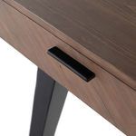 Close-up of black metal drawer handle next to angled metal leg