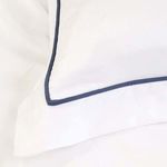 Close-up of white pillowcase corner showing navy blue satin edging detail