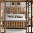 Viewing bed through open glass and wood framed double doors revealing the bedside lamps and artwork above headboard
