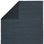 Back corner flipped to reveal black non-slip backing contrast on deep blue rug front.
