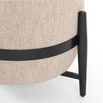 Detailed close-up of black wooden band attached to beige fabric of Sia Ottoman