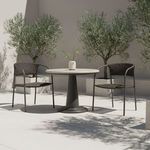 Two outdoor dining chairs placed around round small table on patio with olive trees behind