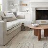 Lumbar pillow placed on light beige sofa with other cushions and a round wooden coffee table in front
