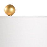 Close-up of the antique gold leaf round finial atop the off-white linen shade