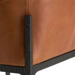 Close-up of leather upholstery meeting hammered iron frame corner