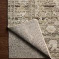Corner lifted to reveal the rug's backing and thickness on a dark wood floor
