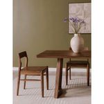 Owing Dining Chair next to matching dining table in room with green wall and artwork