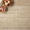 Close-up of Jamie Natural Sand Rug with bowls of onions and garlic showing woven detail and natural fiber texture