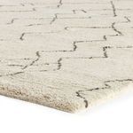 Close-up angled view showing thick pile and hand-knotted texture of cream rug with dark lines