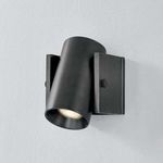 Nowra Wall Sconce angled downward with visible lit bulb in distressed bronze finish