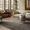 Living room styled shot of the rug with vintage wooden armchair, coffee table, and neutral furnishings