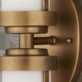 Close-up of brass finish showing round wall mount and textured metal caps surrounding glass tubes