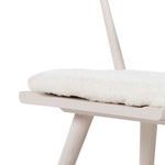 Tight view of plush sheared sheepskin cushion seated on tapered wooden frame edge
