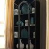 Tall black metal cabinet next to white cushioned armchair in room with wood flooring and natural light