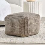 Square pouf styled in modern living room on light rug beside white sofa and textured side table