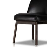 Lower angled view focusing on leather seat corner and dark wood legs