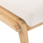 Close detail of textured white upholstery fabric and the wooden joinery beneath the seat