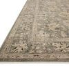 Low-angle close-up of rug corner showing faded floral border and flat pile texture