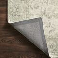 Corner of Rosette rug flipped over revealing sturdy gray woven backing on hardwood floor