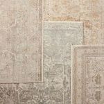 Multiple vintage style rugs layered, with middle rug featuring the Alain Medallion pattern in gray and cream