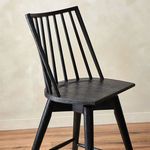 Lewis Swivel Stool angled in soft indoor lighting showing wood grain and back vertical slats