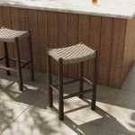 Outdoor stools positioned beside wood-paneled counter with sunlight and shadows on flooring