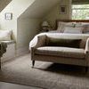 Side angle of the rug under bed with chair near a window seat in attic bedroom