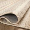 Corner fold of rug reveals texture and woven backing material with hand-tufted wool pile
