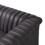 Close-up on padded rolled arm corner with vertical channels in dark gray leather