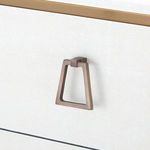 Close-up of trapezoidal brass drawer pull on textured white lacquered linen drawer front