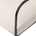 Close-up on black hammered iron armrest and cream fabric seat cushion corner
