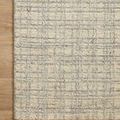 Close-up of Polly Antique Mist rug edge laying on warm wood flooring.