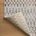 Rug corner lifted displaying woven backing and edge stitching on wood surface