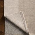 Corner flipped to show underside and attached rug pad on hardwood floor