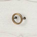Close-up of round metal drawer pull with antique brass finish against sailcloth textured drawer front