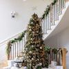 ornaments displayed on a decorated Christmas tree with wrapped gifts underneath in a bright home interior