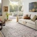 Rug in a bright living room with a sofa, pillows, and large window showing outdoor greenery