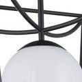 Close-up of black powder-coated curved metal supports and globe cap above opaque white globe