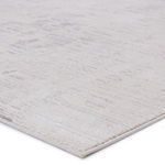 Close-up view of rug edge showing low pile and fine stitched binding in ivory and gray tones