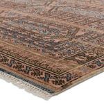 Close-up on pink and beige wool rug corner showing detailed tribal border and fringe