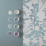 Close-up showing paint cans and samples beside wallpaper to highlight coordinate color palette