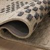 Rolled edge of Bradley rug exposing thick wool pile and black non-slip backing underneath