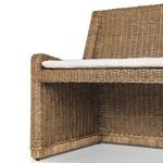 Close-up top perspective of thick beige cushion with tufting and edge piping on rattan frame