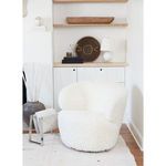 Small white spherical lamp placed on shelf next to modern white upholstered chair in bright room