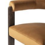 Close-up of chair’s armrest seam and cushioned edge against dark oak frame