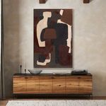 Abstract painting hanging above wooden sideboard in warm-toned room with candleholders and bowl
