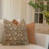 Pillow styled on beige sofa with another solid peachy pink pillow and home interior background